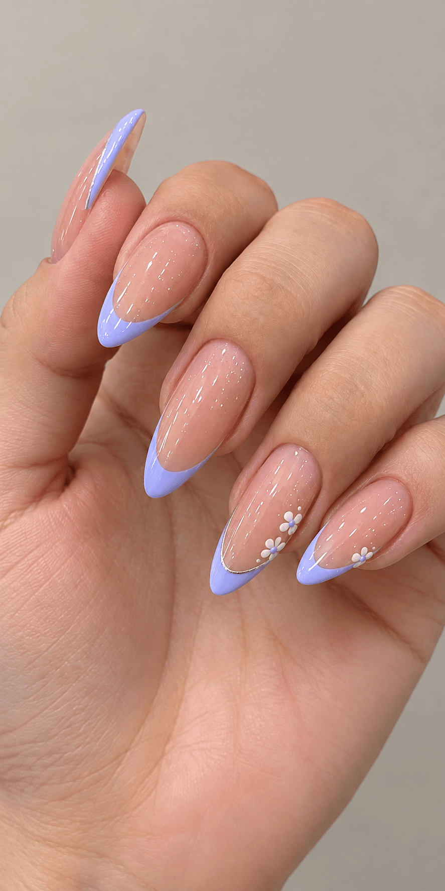 Almond-shaped nails in a glossy nude base with lavender French tips and a delicate white daisy accent on two fingers